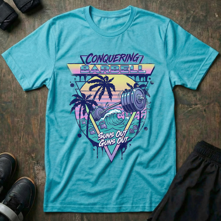 Suns Out Guns Out tee in Tahiti: a barbell rising from ocean waves with palm trees silhouetted against a neon sunset