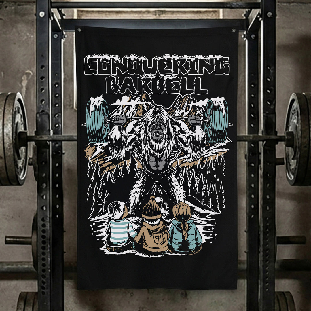 Yeti Squats Flag - Polyester Flag, vertical black gym flag with yeti squatting a loaded barbell among snowy peaks - Conquering Barbell