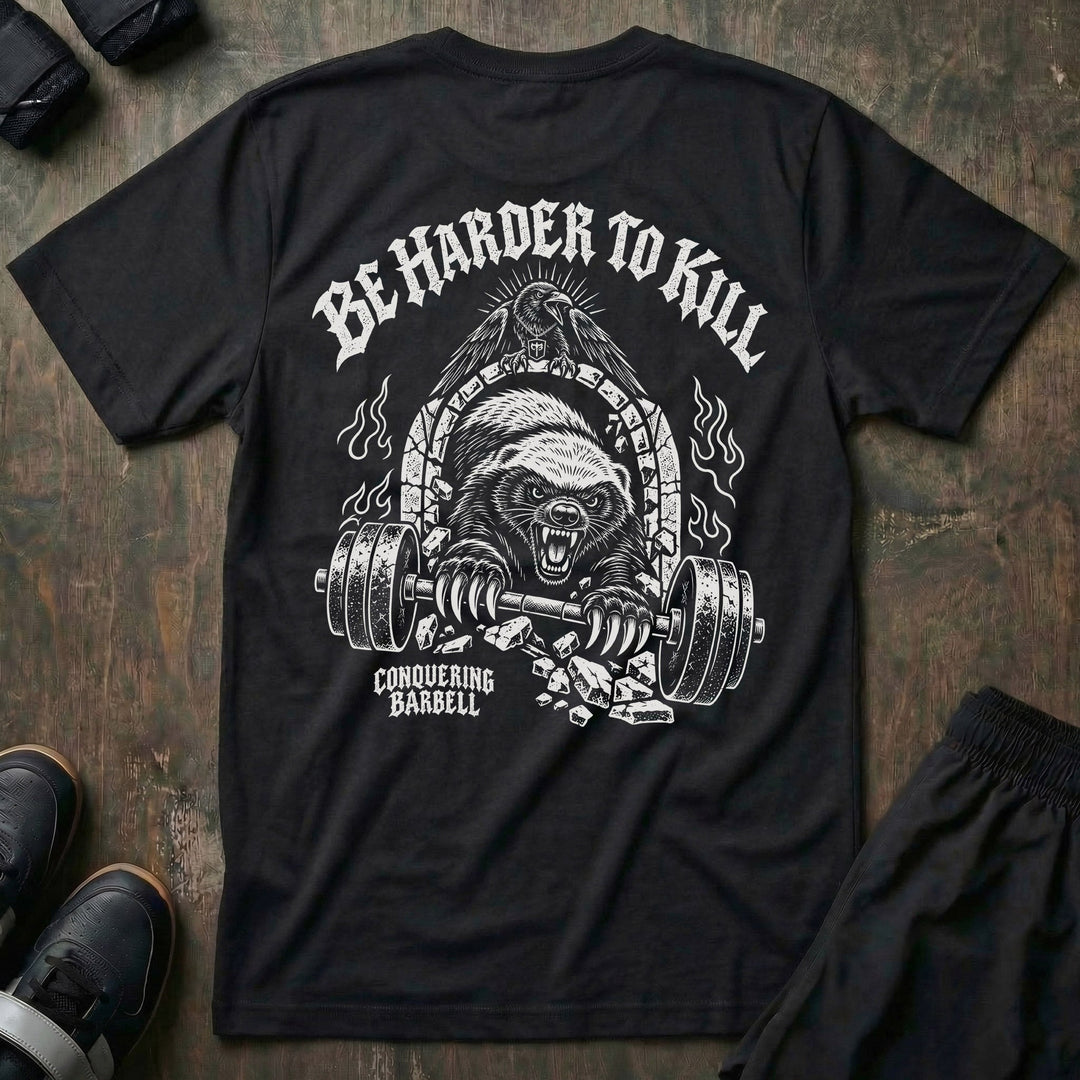 Be Harder to Kill Honey Badger tee in Black: a snarling honey badger bursting through a stone arch with a loaded barbell