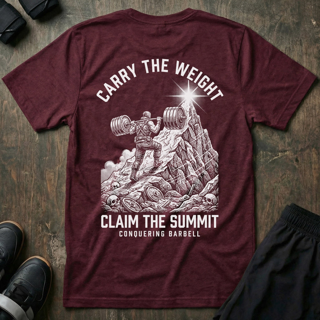 Carry the Weight, Claim the Summit tee in Maroon: an armored lifter hauling a loaded barbell up a jagged mountain toward
