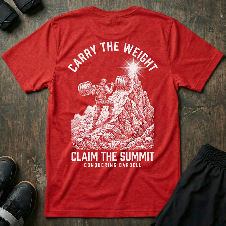 Carry the Weight, Claim the Summit tee in Red: an armored lifter hauling a loaded barbell up a jagged mountain toward