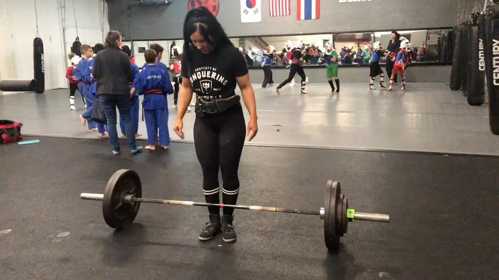 @britttlifts with a loaded deadlift bar in a Conquering Barbell tee