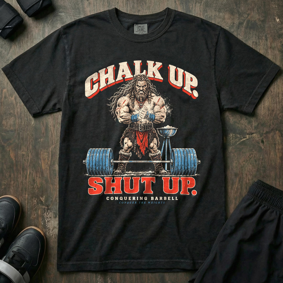 Chalk Up Shut Up - Relaxed Fit Tee front graphic in Black with a barbarian clapping chalk over a loaded barbell - Conquering Barbell