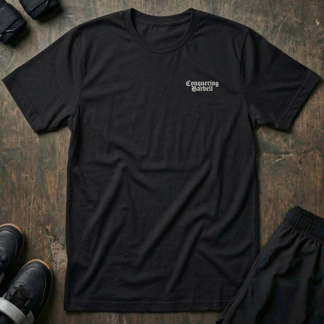 Conquer or Die Monk tee in Black: a winged warrior angel kneeling over a barbell inside a gothic archway