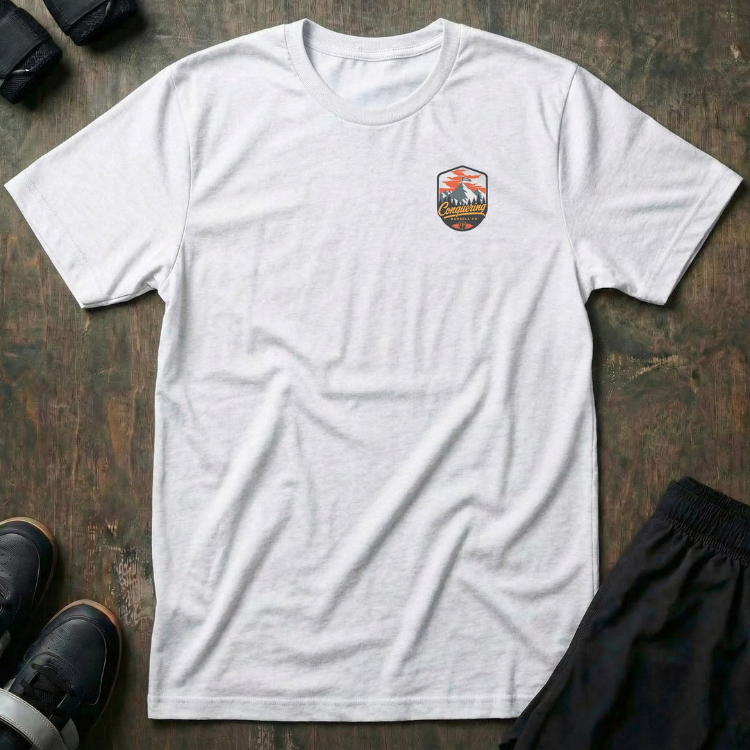 Conquer the Summit tee: a bold outdoor badge with snow-capped peaks above a pine tree line