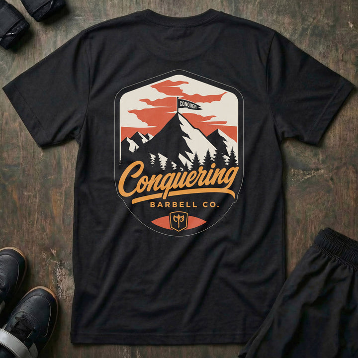 Conquer the Summit tee in Black: a bold outdoor badge with snow-capped peaks above a pine tree line