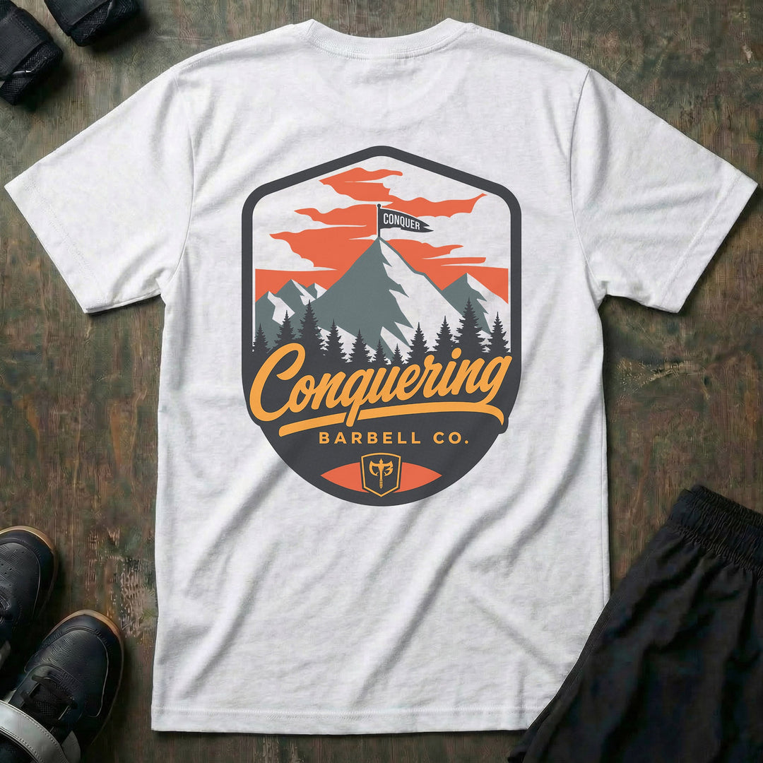 Conquer the Summit tee in White: a bold outdoor badge with snow-capped peaks above a pine tree line