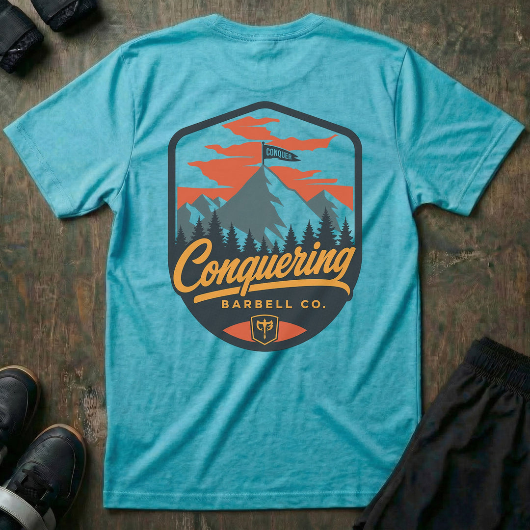 Conquer the Summit tee in Tahiti: a bold outdoor badge with snow-capped peaks above a pine tree line
