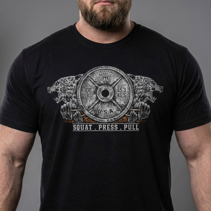 Conquering Barbell Dueling Bears tee in Black: two roaring grizzlies flanking an Olympic weight plate