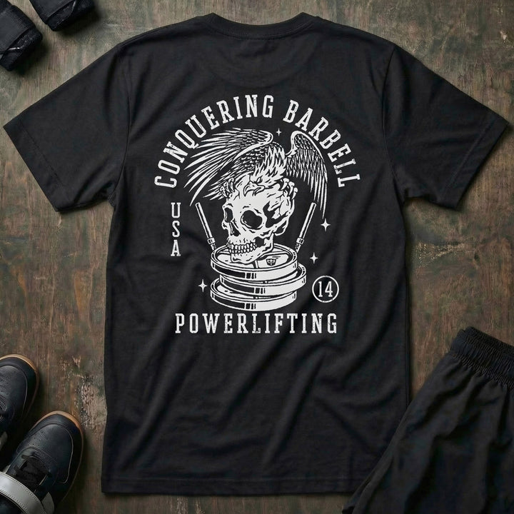 Conquering Barbell Eagle tee in Black: an eagle with spread wings perched on a skull atop stacked plates