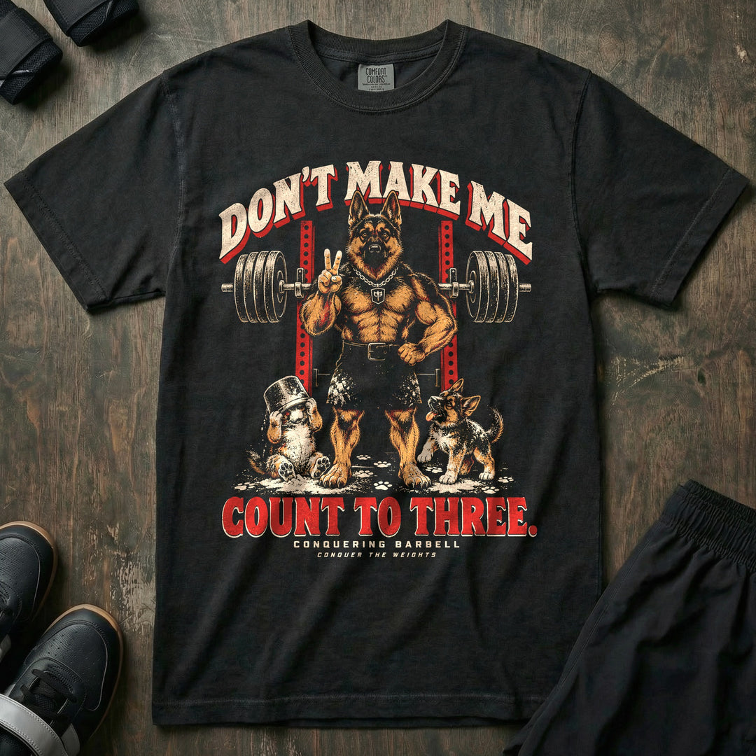 Don't Make Me Count to Three - Relaxed Fit Tee front graphic in Black with a German shepherd dad holding up two fingers in front of a squat rack while two puppies play in spilled chalk - Conquering Barbell