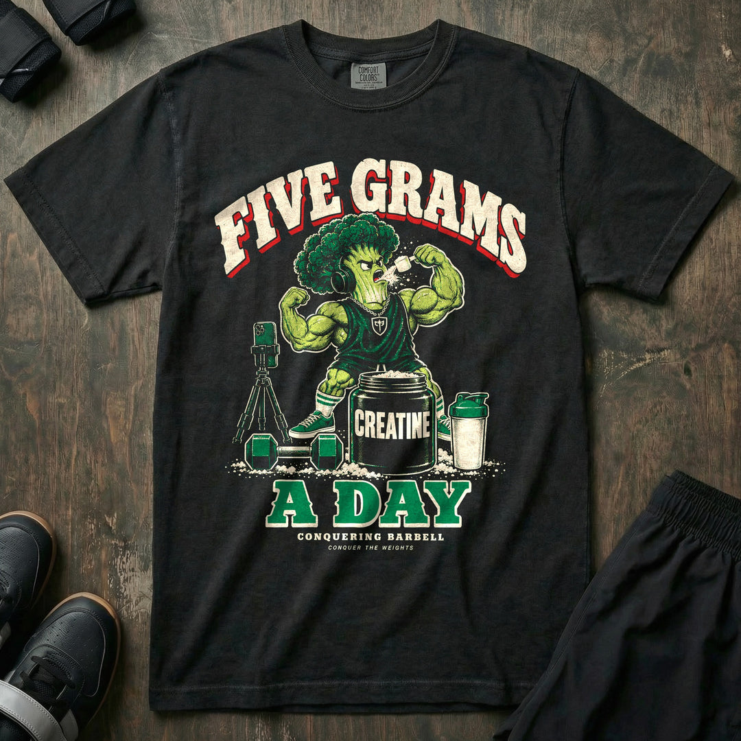 Five Grams a Day - Relaxed Fit Tee front graphic in Black with a muscular broccoli in headphones dry scooping beside a tub labeled creatine - Conquering Barbell