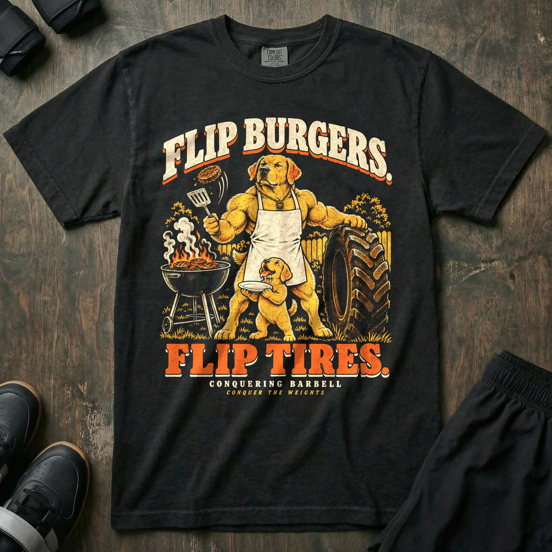 Flip Burgers. Flip Tires - Relaxed Fit Tee front graphic in Black with a golden retriever dad in an apron flipping a burger at a grill while leaning on a tractor tire as a puppy holds a plate - Conquering Barbell