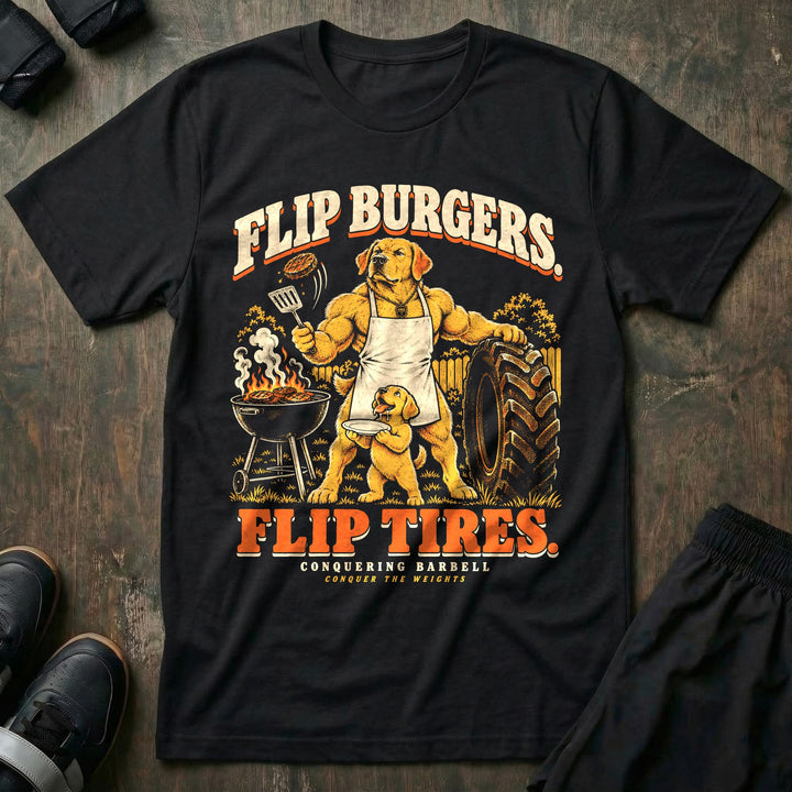 Flip Burgers. Flip Tires - Tee front graphic in Black with a golden retriever dad in an apron flipping a burger at a grill while leaning on a tractor tire as a puppy holds a plate - Conquering Barbell