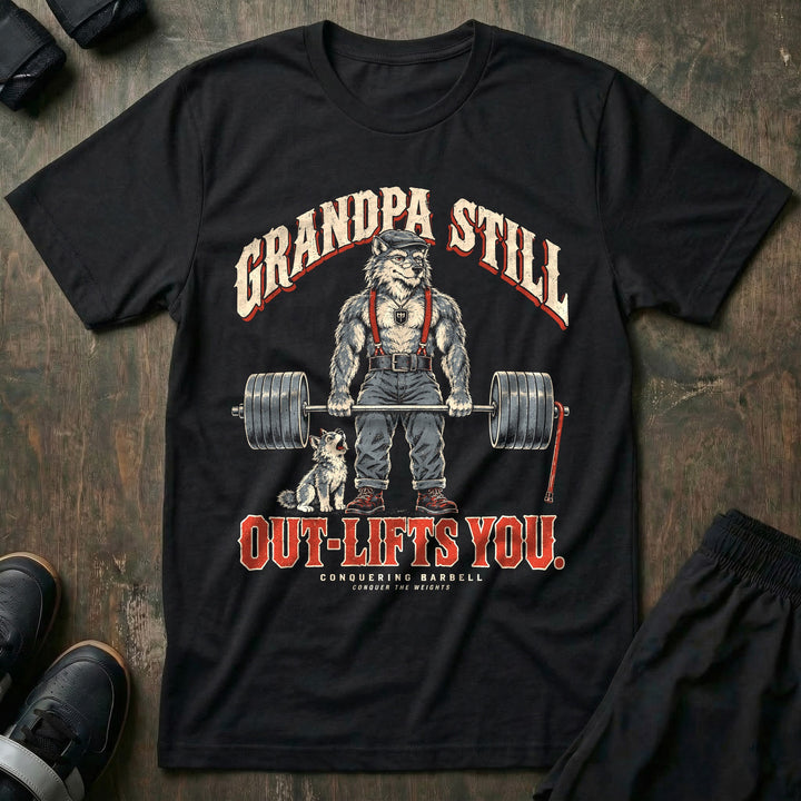 Grandpa Still Out-Lifts You - Tee front graphic in Black with a gray wolf grandpa in a flat cap and suspenders deadlifting a loaded barbell with a cane leaning on it and a wolf pup howling - Conquering Barbell