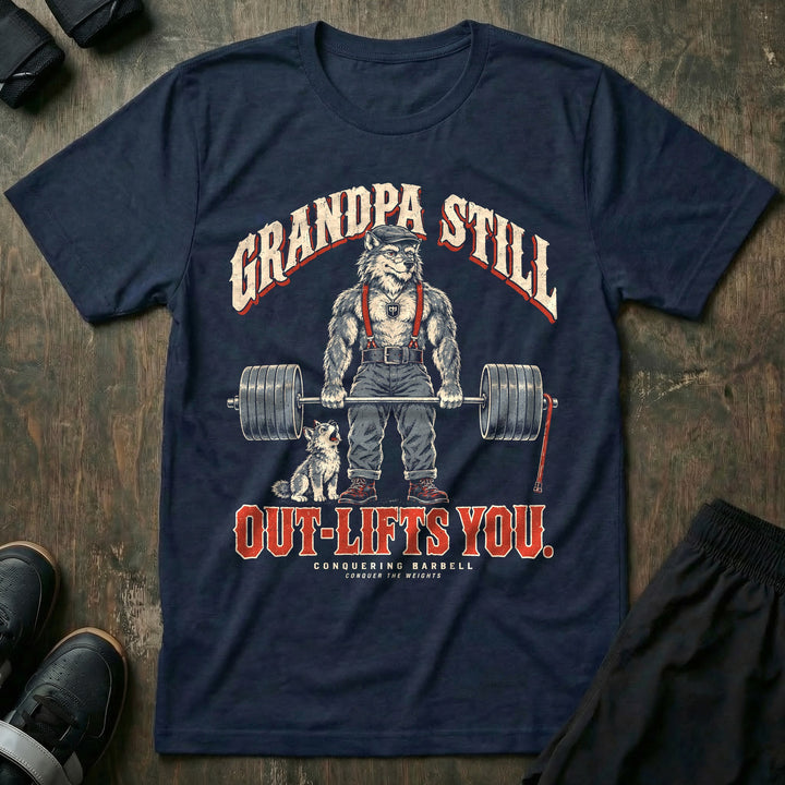 Grandpa Still Out-Lifts You - Tee front graphic in Navy with a gray wolf grandpa in a flat cap and suspenders deadlifting a loaded barbell with a cane leaning on it and a wolf pup howling - Conquering Barbell