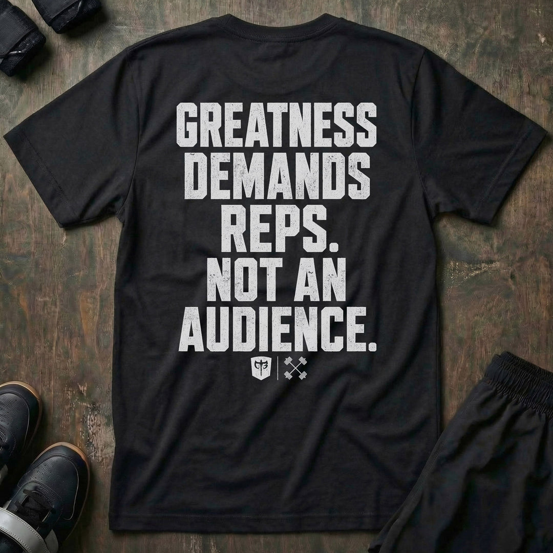 Greatness Demands Reps. Not an Audience. tee in Black: the full statement in oversized distressed block lettering stacked