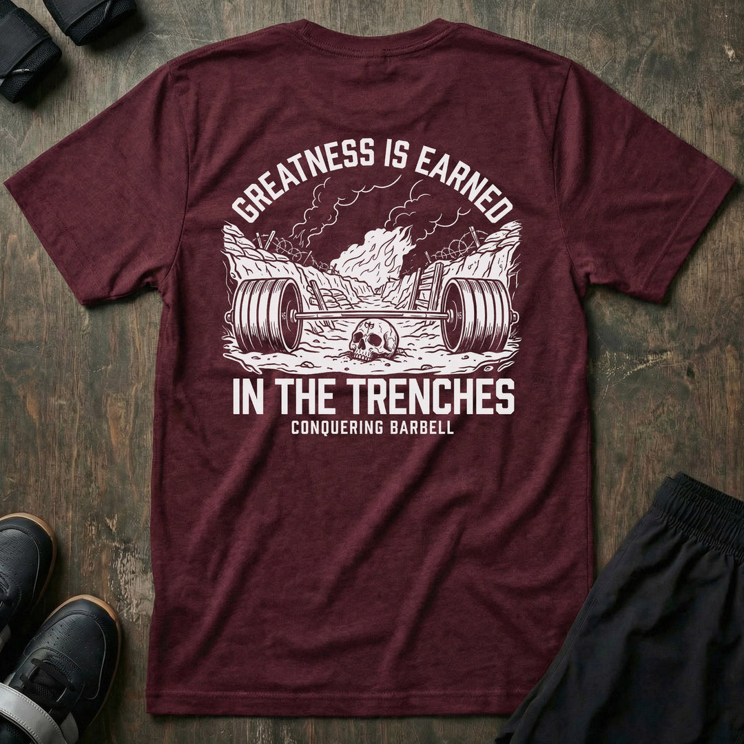 Greatness is Earned in the Trenches tee in Maroon: a loaded barbell lying in a war trench with a skull beside it