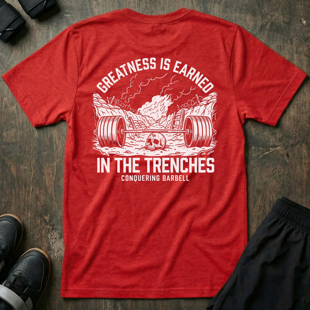 Greatness is Earned in the Trenches tee in Red: a loaded barbell lying in a war trench with a skull beside it