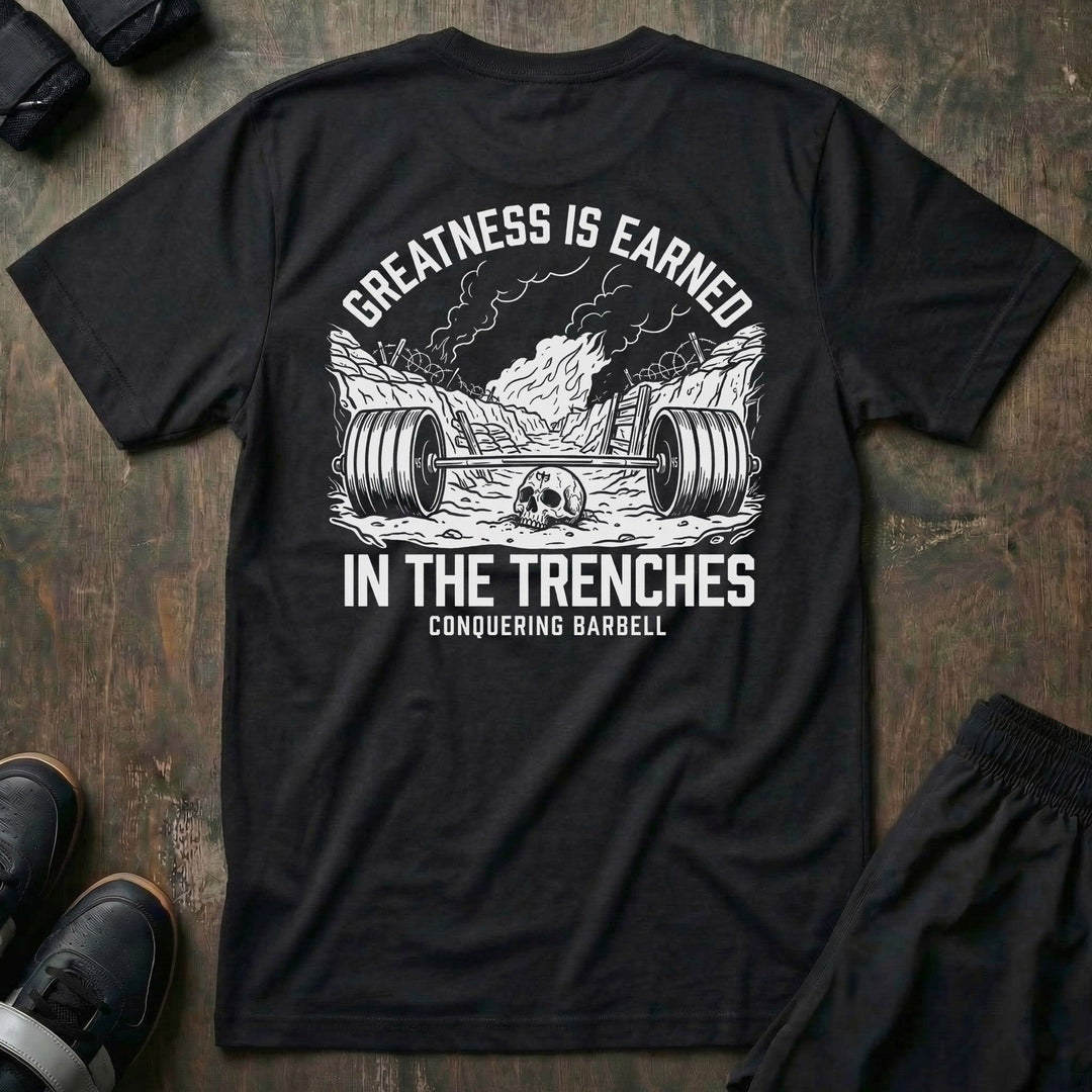 Greatness is Earned in the Trenches tee in Black: a loaded barbell lying in a war trench with a skull beside it