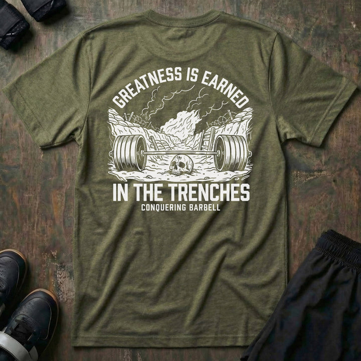 Greatness is Earned in the Trenches tee in Military: a loaded barbell lying in a war trench with a skull beside it