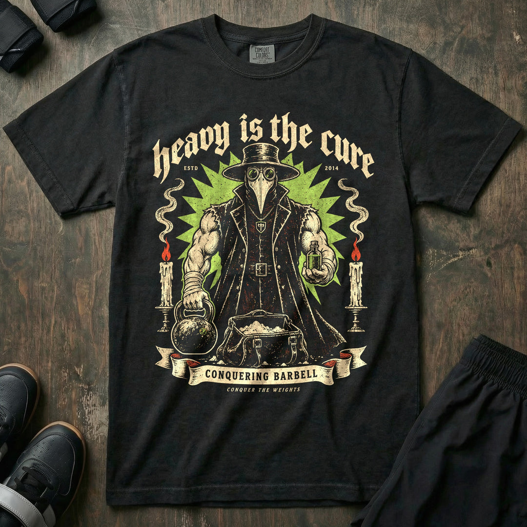 Heavy Is the Cure - Relaxed Fit Tee front graphic in Black with a muscular plague doctor holding a kettlebell and a vial - Conquering Barbell