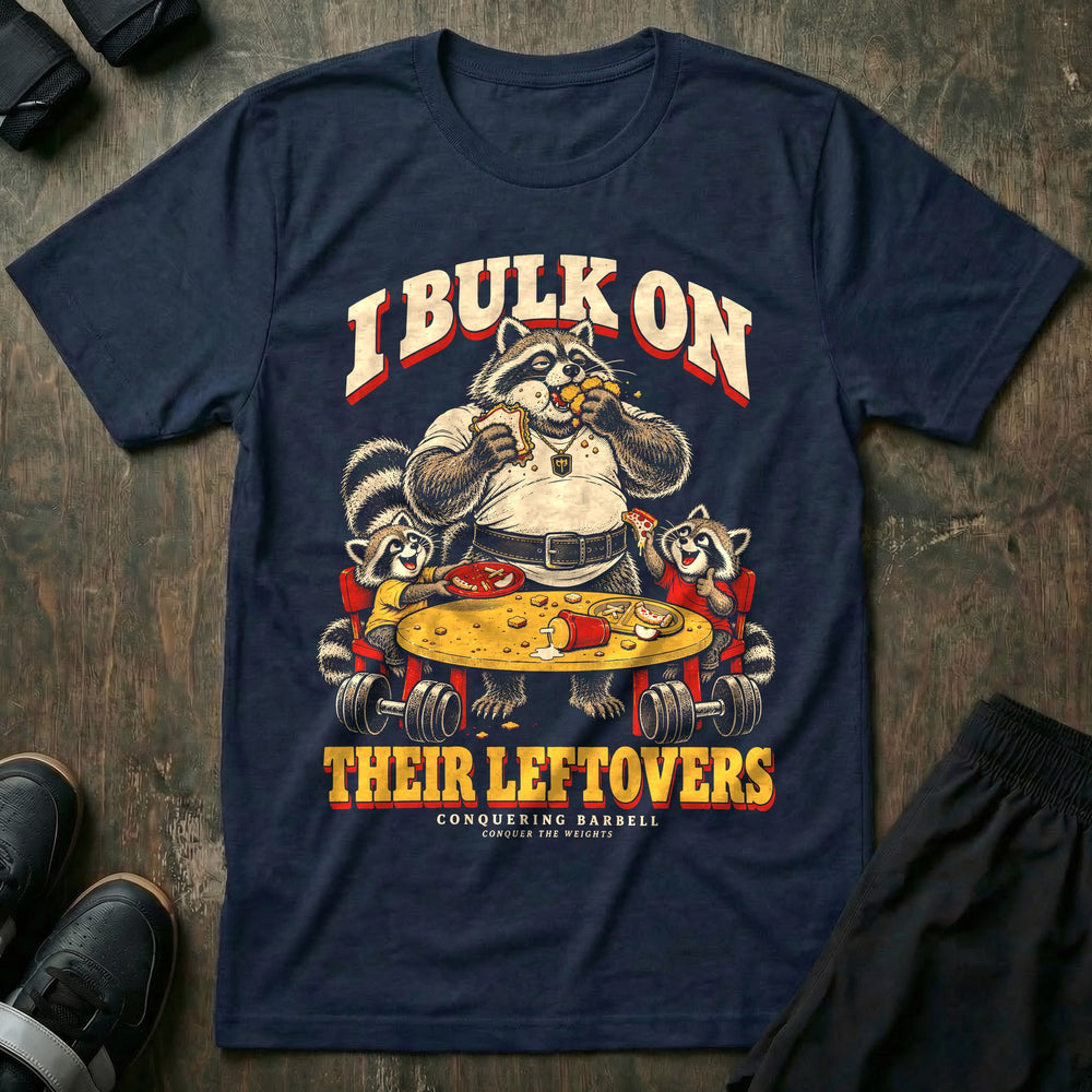 I Bulk on Their Leftovers - Tee front graphic in Navy with a heavyset raccoon dad eating a sandwich and nuggets at the kids' table while two young raccoons laugh - Conquering Barbell