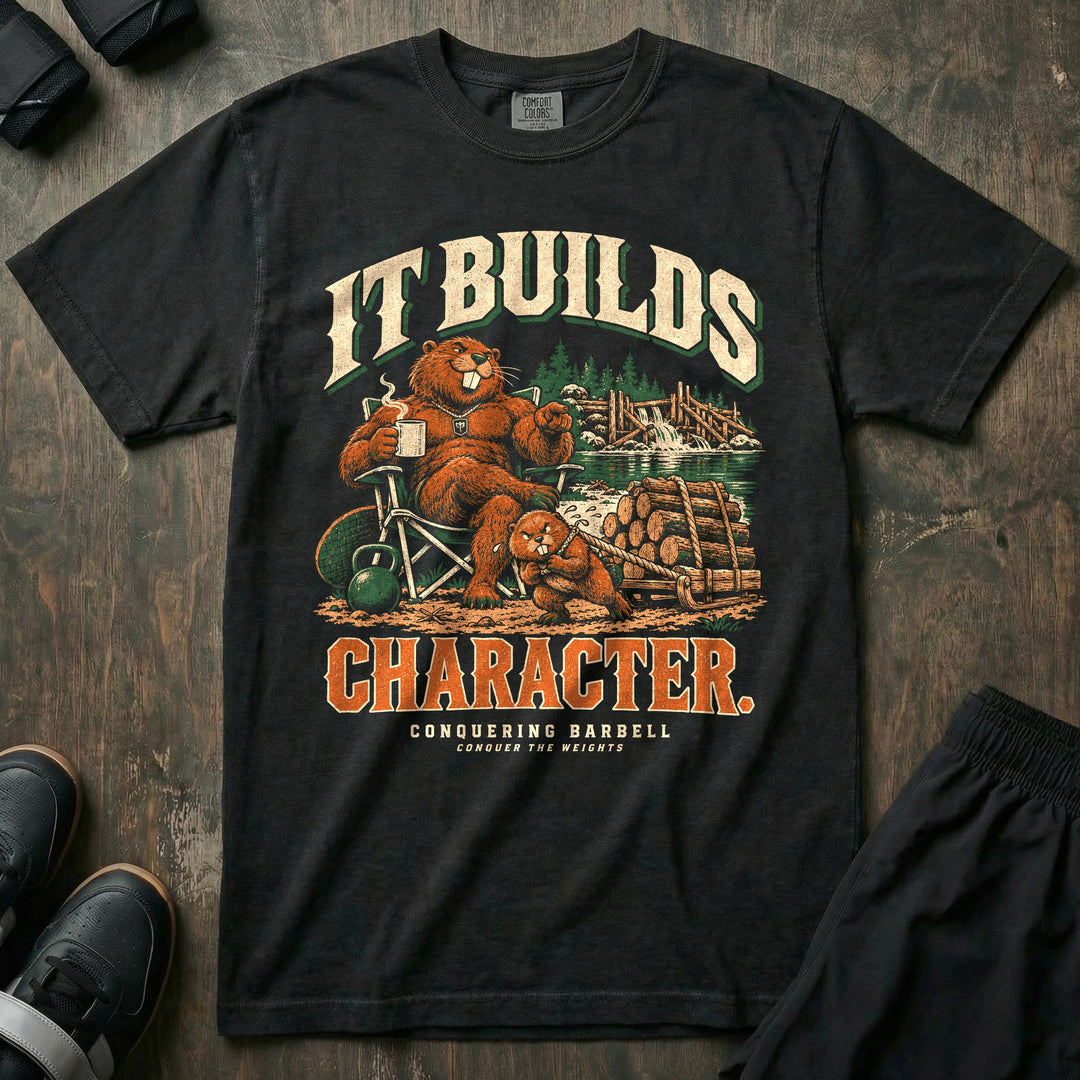 It Builds Character - Relaxed Fit Tee front graphic in Black with a beaver dad sitting in a camp chair with coffee while a young beaver pulls a sled loaded with logs near a dam - Conquering Barbell