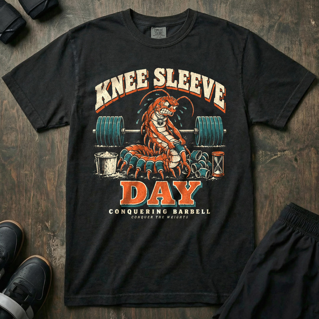 Knee Sleeve Day - Relaxed Fit Tee front graphic in Black with a sweating centipede pulling knee sleeves onto its many legs in front of a loaded barbell - Conquering Barbell