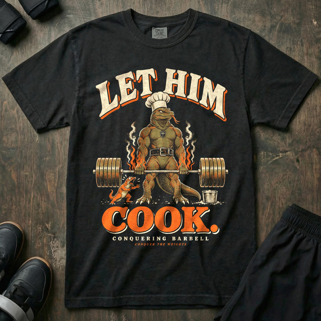 Let Him Cook - Relaxed Fit Tee front graphic in Black with a Komodo dragon in a chef hat at deadlift lockout while a small lizard cheers - Conquering Barbell