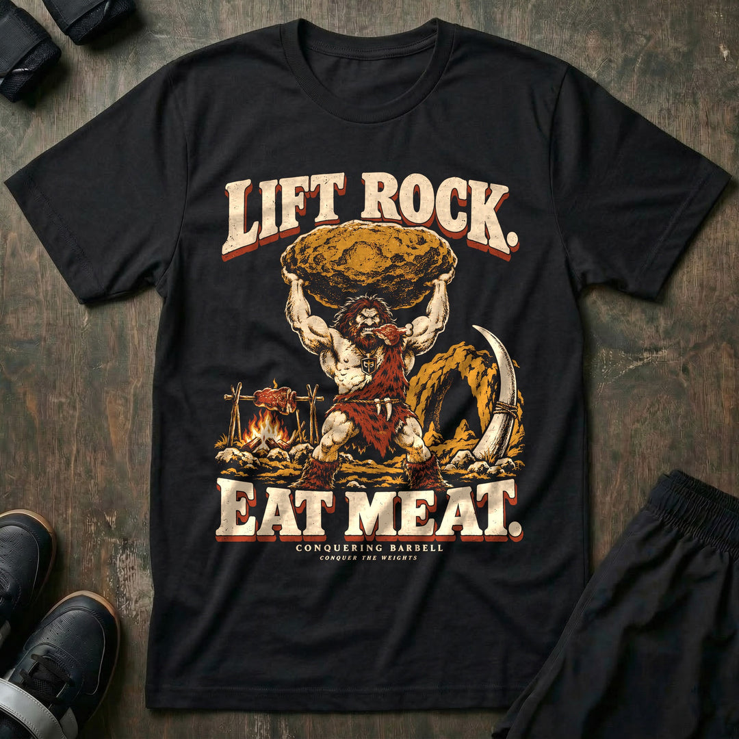 Lift Rock Eat Meat - Tee front graphic in Black with a caveman holding a boulder overhead beside meat roasting on a spit - Conquering Barbell