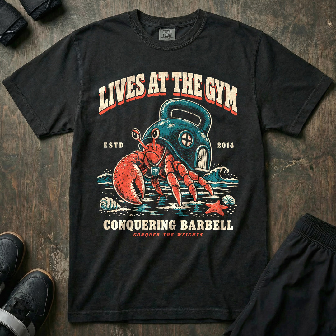 Lives at the Gym - Relaxed Fit Tee front graphic in Black with a hermit crab living inside a kettlebell on the beach - Conquering Barbell