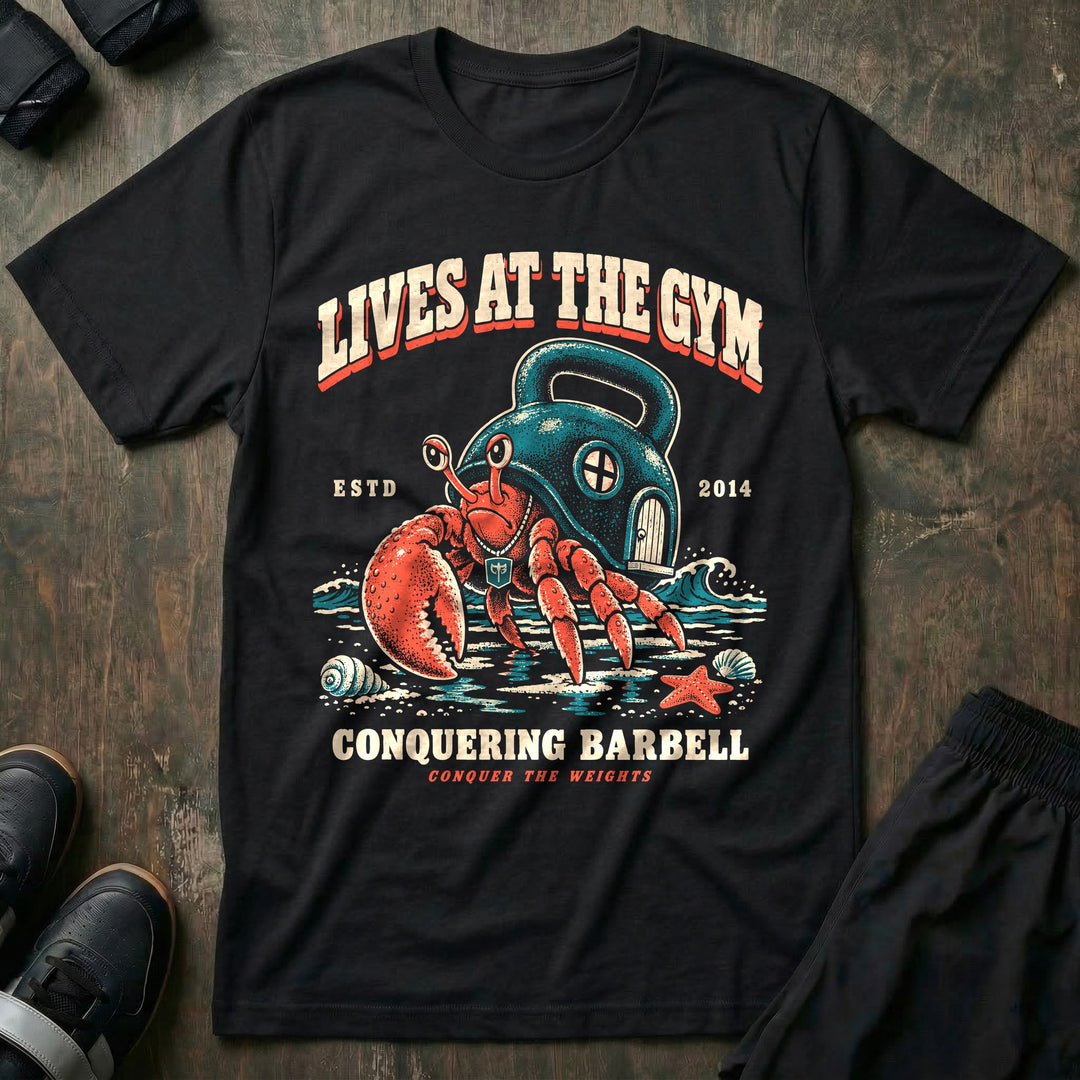 Lives at the Gym - Tee front graphic in Black with a hermit crab living inside a kettlebell on the beach - Conquering Barbell