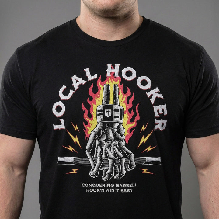 Local Hooker tee in Black: a skeleton hand locked in a hook grip on a barbell in front of roaring flames and lightning