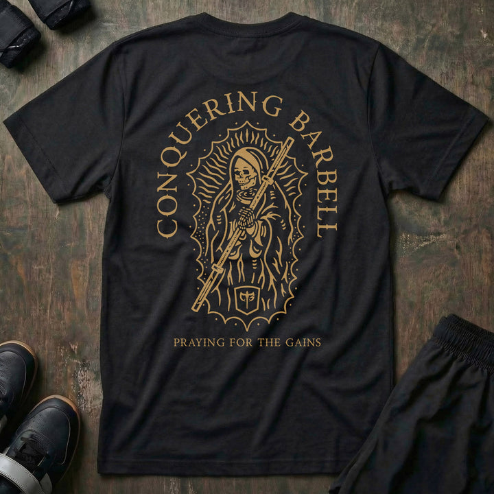 Mother of Iron tee in Black: a skeletal saint draped in robes clutching a barbell sleeve inside an ornate halo frame