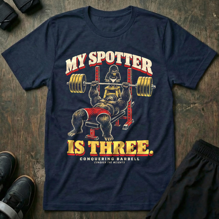 My Spotter Is Three - Tee front graphic in Navy with a gorilla dad bench pressing a loaded barbell while a baby gorilla in a diaper spots him from a step stool - Conquering Barbell