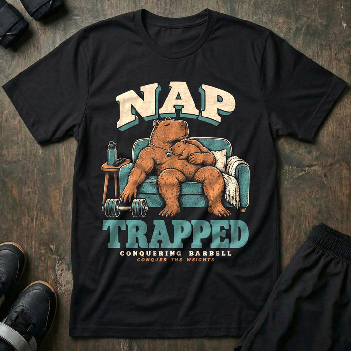 Nap Trapped - Tee front graphic in Black with a capybara dad asleep in an armchair with a baby capybara sleeping on his chest and a dumbbell on the floor - Conquering Barbell