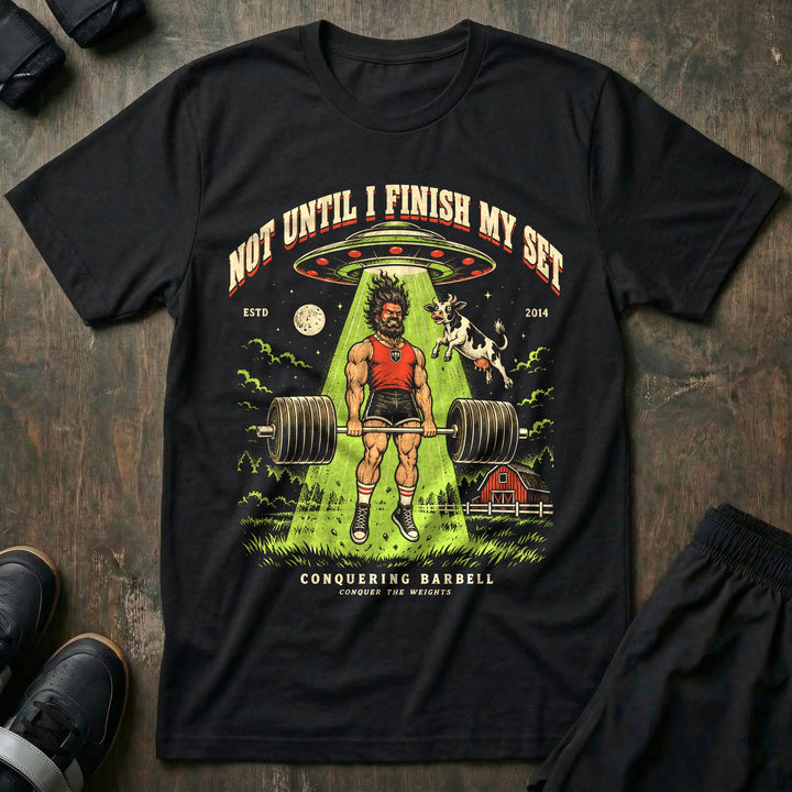 Not Until I Finish My Set - Tee front graphic in Black with a lifter finishing a deadlift while a UFO tractor beam lifts him and a cow - Conquering Barbell