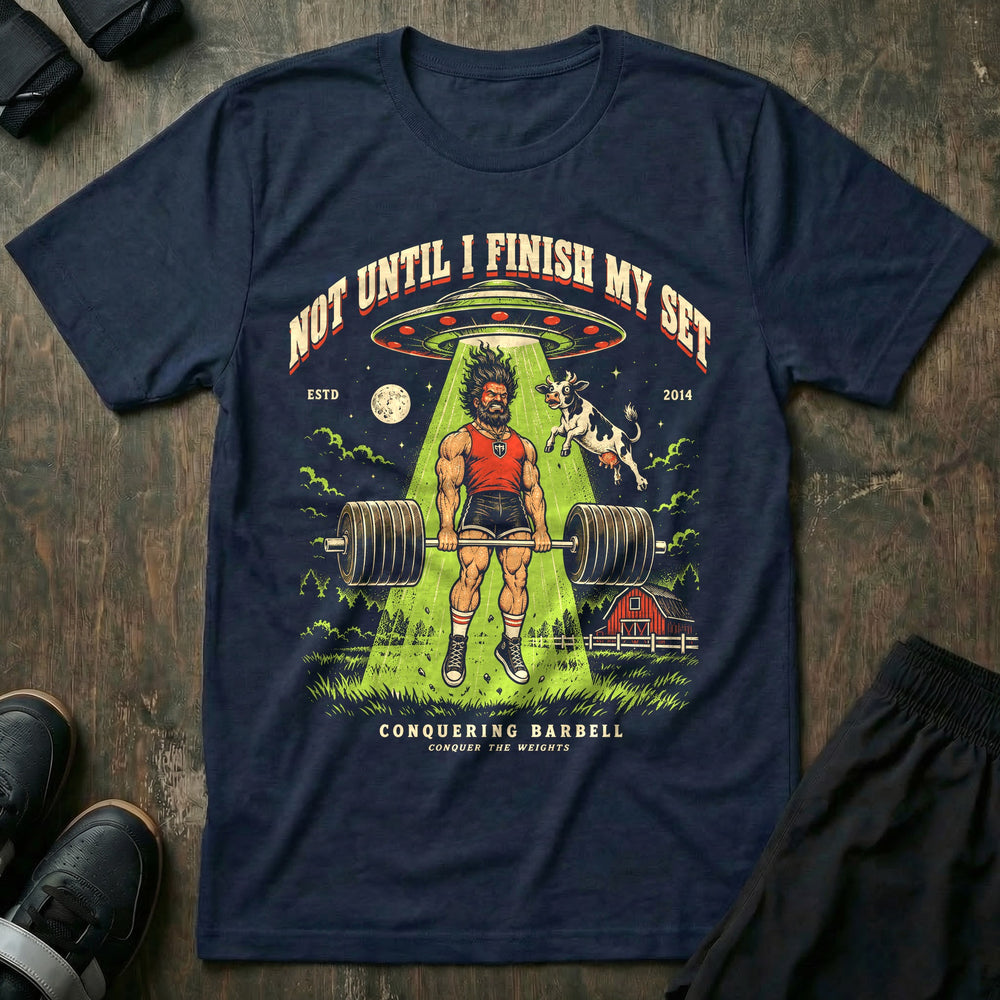 Not Until I Finish My Set - Tee front graphic in Navy with a lifter finishing a deadlift while a UFO tractor beam lifts him and a cow - Conquering Barbell