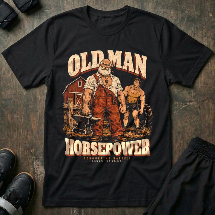 Old Man Horsepower - Tee front graphic in Black with a white-bearded farmer in overalls carrying an anvil in one hand while a young lifter strains at a tractor tire - Conquering Barbell