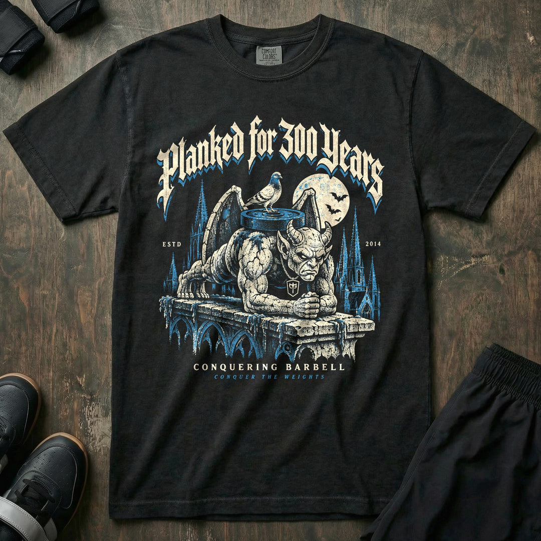 Planked for 300 Years - Relaxed Fit Tee front graphic in Black with a stone gargoyle holding a weighted plank on a cathedral ledge - Conquering Barbell
