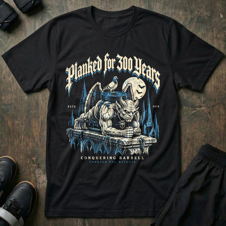 Planked for 300 Years - Tee front graphic in Black with a stone gargoyle holding a weighted plank on a cathedral ledge - Conquering Barbell