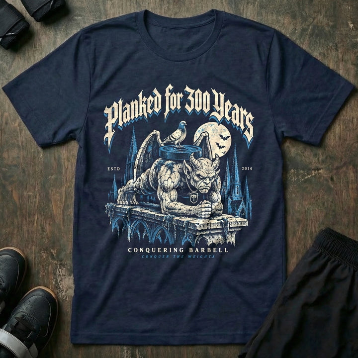 Planked for 300 Years - Tee front graphic in Navy with a stone gargoyle holding a weighted plank on a cathedral ledge - Conquering Barbell