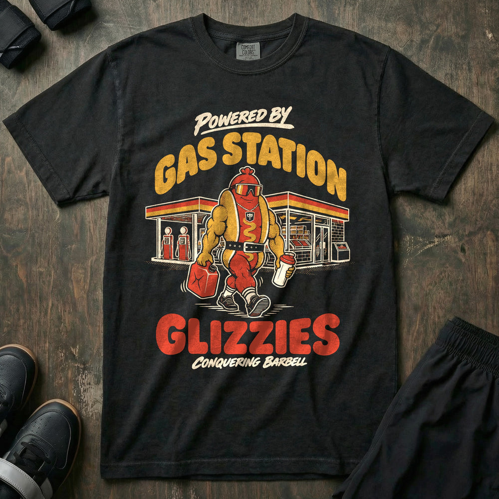 Powered by Gas Station Glizzies - Relaxed Fit Tee front graphic in Black with a muscular hot dog lifter walking out of a gas station under POWERED BY GAS STATION GLIZZIES - Conquering Barbell