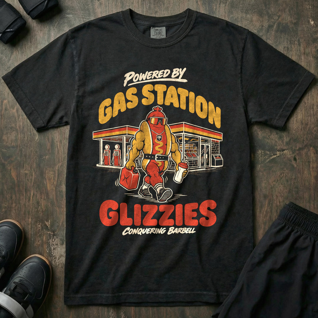 Powered by Gas Station Glizzies - Relaxed Fit Tee front graphic in Black with a muscular hot dog lifter walking out of a gas station under POWERED BY GAS STATION GLIZZIES - Conquering Barbell