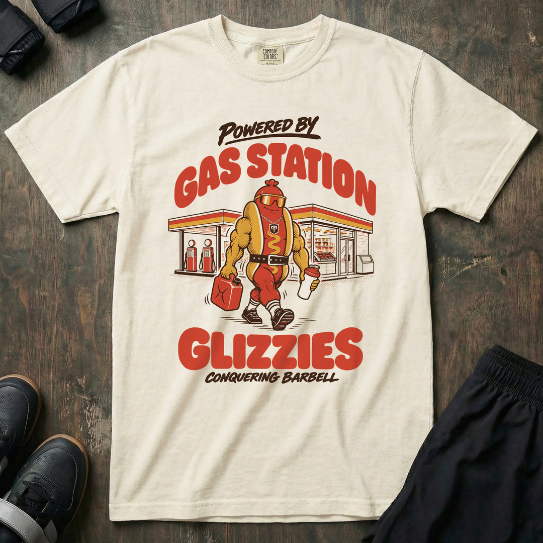 Powered by Gas Station Glizzies - Relaxed Fit Tee front graphic in Ivory with a muscular hot dog lifter walking out of a gas station under POWERED BY GAS STATION GLIZZIES - Conquering Barbell