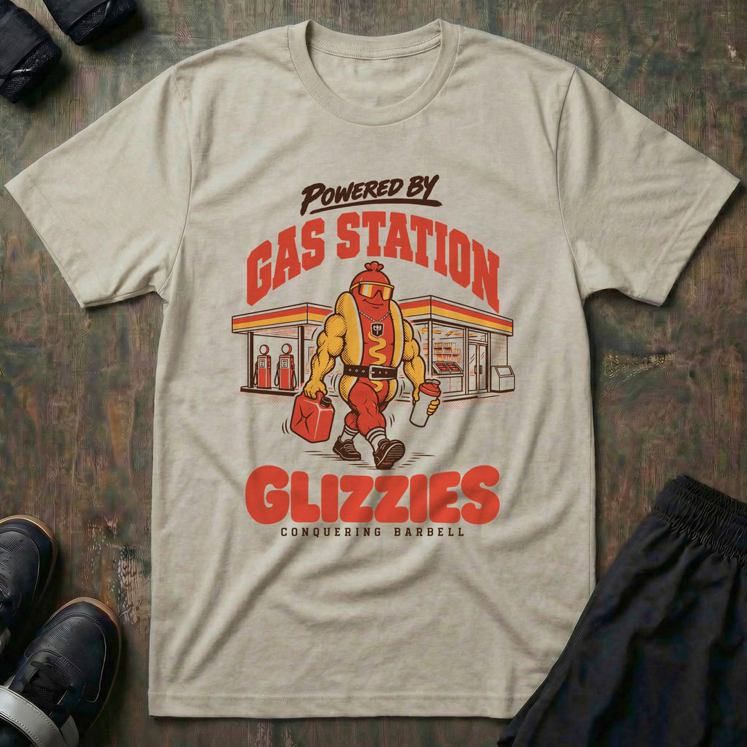 Powered by Gas Station Glizzies - Tee front graphic in Sand with a muscular hot dog lifter walking out of a gas station under POWERED BY GAS STATION GLIZZIES - Conquering Barbell