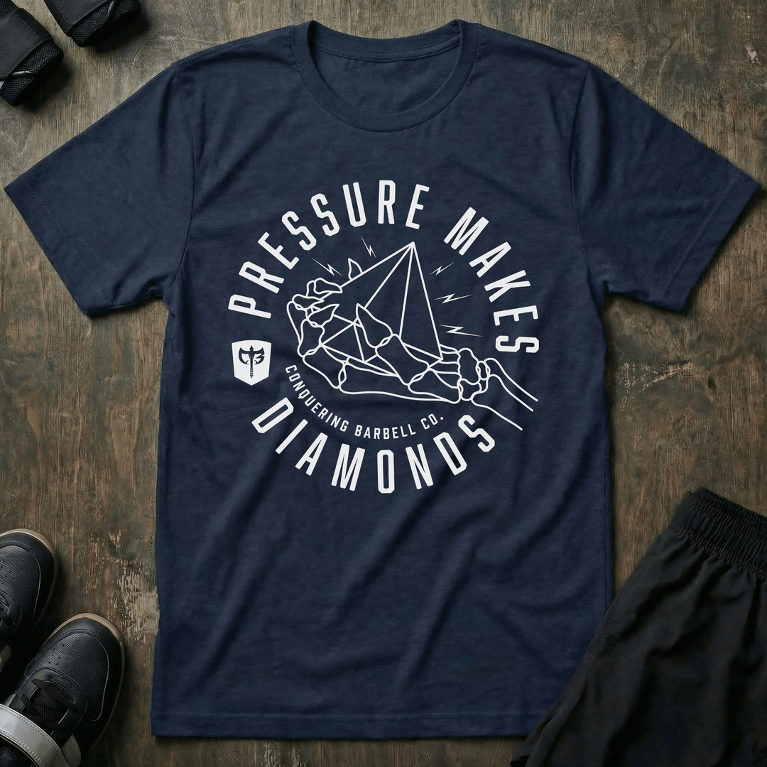 Pressure Makes Diamonds tee in Navy: a clenched fist holding a cut diamond inside a bold circular badge