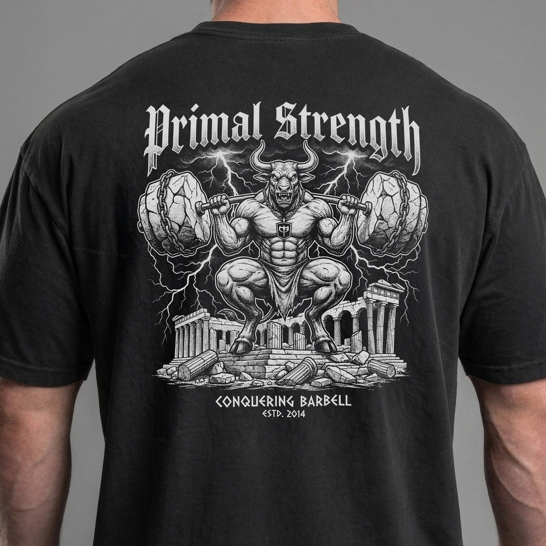 Primal Strength Minotaur relaxed fit tee in Black: a massive minotaur squatting a barbell loaded with boulder plates