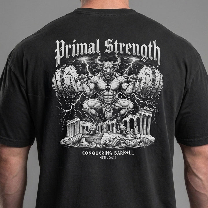 Primal Strength Minotaur relaxed fit tee in Black: a massive minotaur squatting a barbell loaded with boulder plates